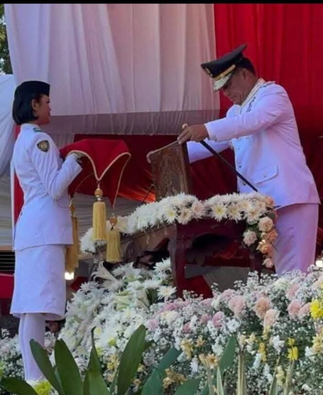 
Foto - Gubernur Sulut Yulius Selvanus Selaku Inspektur Upacara HUT RI Ke- 80 Saat Memberikan Benderah Merah Putih Kepada Pembawa Baki Jouna Milka Liwoso Siswa Kelas XI SMA Negeri 1 Manado Minggu 17 Agustus 2025